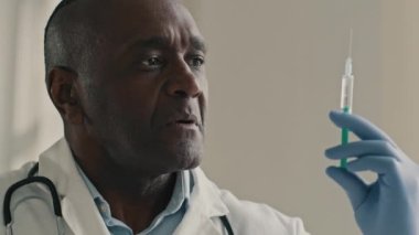 Profesyonel olgun Afrikalı doktor etnik erkek cerrah anestezi uzmanı. Laboratuvarda yeni aşıyı test eden anestezi uzmanı. Antibiyotik şırınga aşısı.