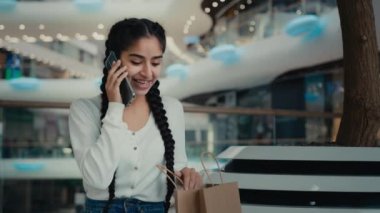 Arabistanlı bayan müşteri alıcısı kadın alışverişçi alışveriş merkezindeki telefon konuşmaları lüks giyim mağazasından hediye çantaları satın almalar indirimli satışlar hakkında konuşmalar cep telefonu bağlantıları.