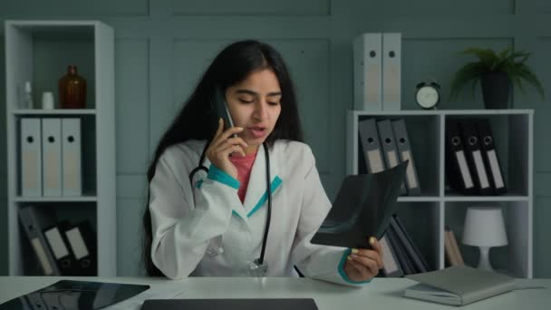 年轻的阿拉伯医生妇女全科医生放射科医生谈论手机咨询病人远程看X光骨骼图像断层扫描结果分享好消息医疗专业诊断 — 图库视频影像