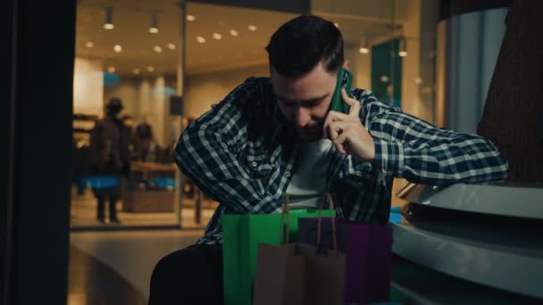 男性買い物客アラビアの若い男のお店の顧客はショッピングモールトーク携帯電話に座っている店舗からのパッケージバッグをリモートで見て通信チェック購入する休日に豪華なギフトプレゼントを購入 — ストック動画