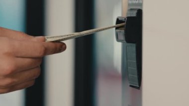 Erkek elini kapat. Bankacılık hizmetinin ATM 'ye girerken yaptığı hataya nakit para banknotu koy. Banka işlemleri hatası.