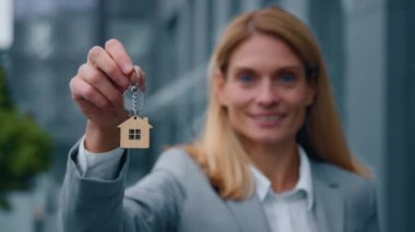 Yeni evin anahtarını gösteren beyaz kadın emlakçı iş kadınına odaklan. Ev satın alırken ev sahibi mutlu mesut evler satar.