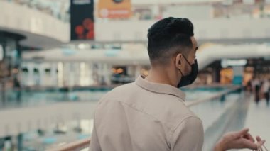 Maskeli, etnik bir adam, Hintli, tıbbi maske takan bir işadamı, alışveriş merkezindeki müşteri müşterisi, elinde çantalarla poz veriyor, hediye paketleri satıyor.