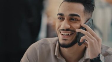 Etnik Hintli gülen cep telefonlu adam telefon cihazıyla konuşuyor. 30 'lu yaşlarda, erkek, yönetici, gülümseyen, gülen, mutlu, cevap veren, konuşan, cep telefonu konuşan.
