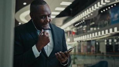Orta yaşlı patron girişimci işadamı. 50 'li yaşlardaki Afrikalı işadamı, tomarlı telefona göz atıyor. Şirkette duruyor.