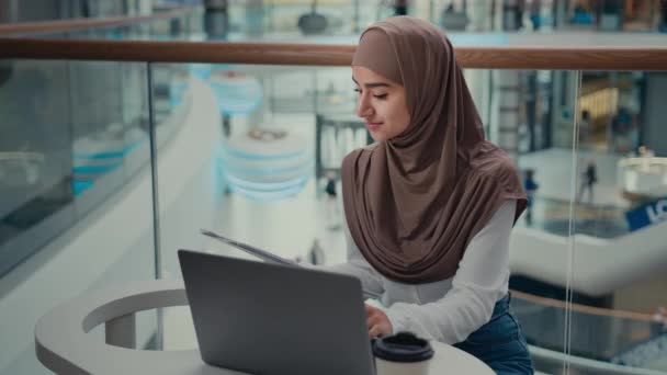 阿拉伯突厥语穆斯林女学生伊斯兰女商人Hijab工作在遥远的笔记本电脑上检查商业文件纸质文件在网上输入电子数据支付账单电子商务 — 图库视频影像