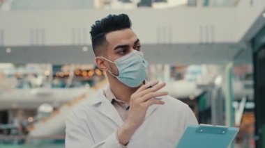 Etnik Hintli doktor, yüz maskesi takan doktor, terapist, cerrah, uzman bilim adamı, hastanede yürüyen bilim adamı, not yazma beklentisiyle bilgi randevusu bekliyor.