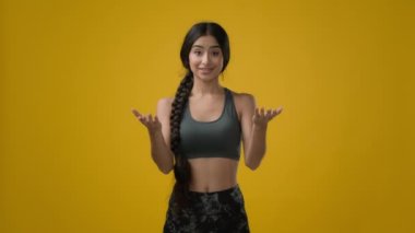 Etnik kadın Hintli sporcu spor eğitmeni bayan sporcu. Stüdyoda kadın sporcu. Kamera karşısında el ve boyun esneme egzersizlerini online olarak açıklamaya çalışıyor.