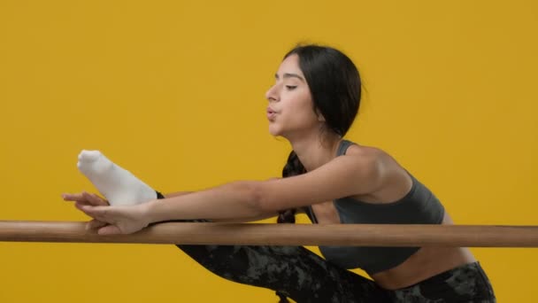 インドのスリムスポーティな女の子のアスリートは ワークアウトを行います女性ダンサーバレリーナ女性で黄色のスタジオ背景ストレッチとともにバレエバレエストレッチ脚の筋肉ダンスクラスで柔軟な運動 — ストック動画