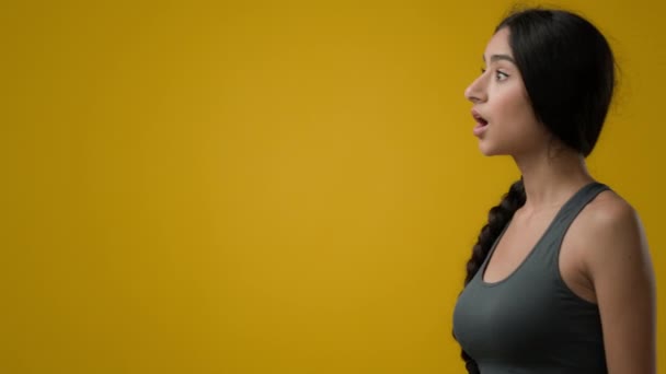 衝撃的な感情的なインドの女性の女の子女性でスタジオで黄色の背景を指して横に空のスコープスペース広告驚き驚くべき見事な見て脇に驚き不信興奮ショック — ストック動画