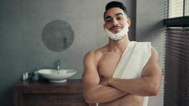ハンサムな面白いですインドヒスパニックラティーナ男30代の筋肉男ありますバスルームに自宅でホテルのシャワーで交差アームとともにカメラを見ますとともに白い泡シェービングジェルで髭面前シェービング — ストック動画