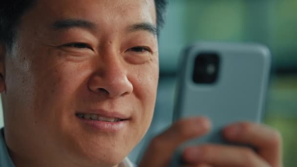 顔を閉じて男性ユーザー千年のアジアの成人男性ビジネスマン正の幸せな笑顔ビジネス人はオフィスで携帯電話でメッセージを送信スマートフォンアプリを使用して 携帯電話でメッセージを送信インターネットで無料のWifi検索ウェブサイト — ストック動画
