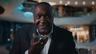 Orta yaşlı etnik girişimci işveren mikrofondaki ses kaydedici ses kaydıyla konuşuyor. Akıllı telefonlu 50 'li yılların Afro-Amerikan işadamı.