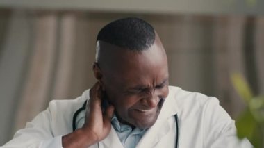 Aşırı çalışan erkek doktor Afrikalı cerrah stajyer doktor ağrılı gerilmiş boyun kasları rahatsız edici gerilim, rahatsız edici osteokondroz.