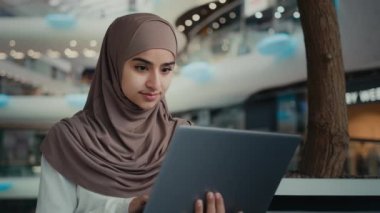İslami Arap Müslüman iş kadını tesettürlü bayan girişimci, alışveriş merkezinde çalışan kız öğrenci dizüstü bilgisayar kullanarak internet arama işi arıyor, internetten uzak öğrenim satın alma emri veriyor.