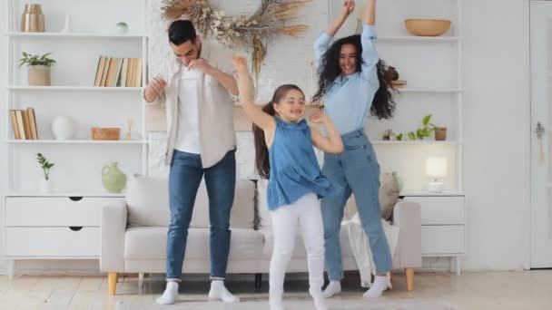 疯狂快乐的多种族家庭父母妈妈爸爸和可爱有趣的活泼的小女孩妈妈和爸爸听音乐跳舞一起欢度家庭派对 — 图库视频影像