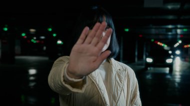 Üzgün, kızgın, genç, umutsuz, Ukraynalı, beyaz, kadın bayan, el hareketlerini durdurup, savaş karşıtı tavırlar sergiliyor. Karanlık sığınak otoparkında savunma engeli yok.