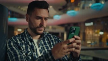 Kafkasyalı düşünceli İspanyol işadamı cep telefonu ekranına bakan ciddi bir adam akıllı telefon konuşmalarıyla mesaj yazıp alışveriş merkezinde ürün satın alan internet uygulaması.