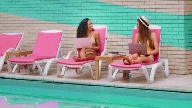 Çok ırklı kadın Kafkasyalı Latin arkadaşlar kadın blogcular serbest yazar turistler güneş altında dinleniyor yaz tatili paylaşımları medya içerikleri internet üzerinden dizüstü bilgisayar kullanımı seyahat sektöründe rezervasyon biletleri