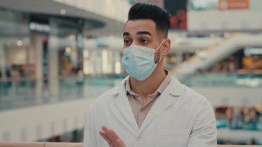 Doktor, erkek, etnik Hintli doktor, maske giymiş laboratuvar önlüğü giymiş. Tanınmaz halde duran kadın, kadın alnına dayanan sıcaklık ölçer. Temassız termometre kovid 19.
