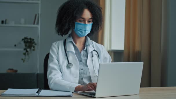 Médica Mulher Africana Étnica Máscara Facial Uniforme Sentar Gabinete Hospital — Vídeo de Stock