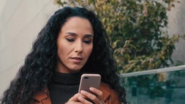 Şehrin dışında yürüyen kadın ciddi bir beyaz kadın iş kadını akıllı telefonuyla sokakta yürüyor. Çevrimiçi harita uygulaması kullanan kadın dışarıda cep telefonuyla sohbet ediyor.