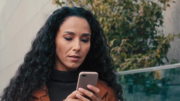 街の閉鎖屋外で歩く女性深刻な白人ヒスパニック系の女性ビジネス女性は オンライン地図アプリの女性を使用してスマートフォンで路上で歩く携帯電話のブラウジングチャットで外を歩く — ストック動画