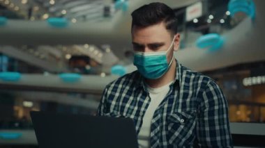 Genç girişimci işadamı serbest çalışan Arap asıllı, koruyucu solunum maskesiyle alışveriş merkezinde sohbet eden, internetteki bilgisayar uygulamasını kullanarak pandemik covid-19 Coronavirus