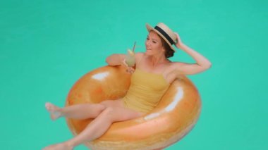 Yüzme havuzunda yüzen sarışın turist mankenli mutlu kız. Meyve suyu kokteyli, ferahlatıcı içecek. Bayan öğrenci yaz tatillerinde deniz suyunu serpti.