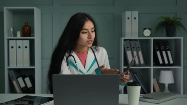 年轻的女放射学家在视频聊天中交谈会诊病人在线分析X射线图像断层扫描结果给医学专业诊断显示骨骼伦琴使用计算机会议应用程序 — 图库视频影像