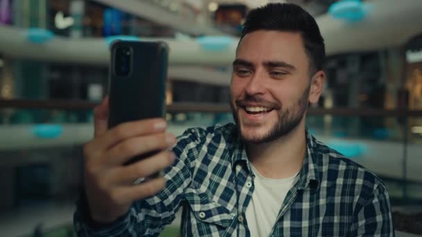 笑顔アラビア語白人男性ブロガービジネスマン携帯電話カメラトークビデオコールでショッピングモール幸せな若い男チャットオンライン記録ブログ使用現代的な技術リモートコミュニケーション — ストック動画