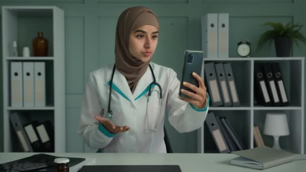 女性アラビア語イスラム教徒の医師女性でヒジャーブ療法士医療大学の学生の話電話記録有用なビデオアドバイスリモート仮想相談は モバイルアプリで遠くを呼び出します — ストック動画