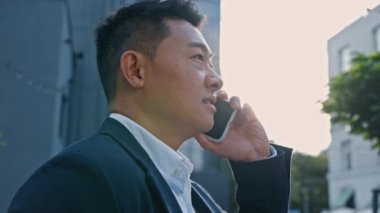 Resmi takım elbiseli Asyalı adamla konuşmak emlakçı müdür iş adamı şehirdeki Koreli işveren ile konuşmak açık havada telefonla cep telefonuyla konuşmak