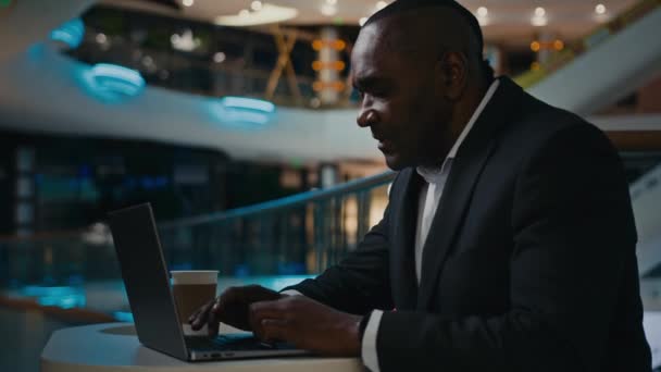 50代半ばのアフリカ人労働者のマネージャーは テーブルの上に無線コンピュータを入力します ラップトップの男性起業家と一緒に働く大人のシニア成熟したビジネスマン遠くの仕事金融スタートアップIt作業オンライン — ストック動画