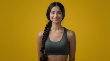 Stüdyoda 20 'li yaşlarda, sporcu, sporcu, sporcu, sporcu, sporcu, koşucu, sarı arka planda, dişlek, gülümseyen, dişlek, mutlu spor mankeni pozu veren bir koşucu.