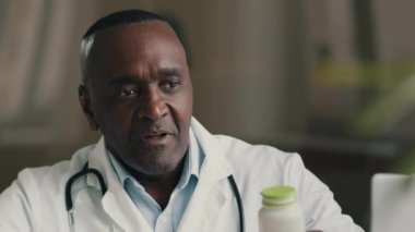 Erkek doktor olgun Afro-Amerikan erkek bakıcı sıhhiyeci hemşire ilaç haplı şişeyi tutuyor antibiyotik ilaç ilavesi bağışıklık için