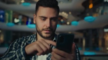 Heyecanlı İspanyol iş adamı telefon ekranını işaret ederek mutlu bir erkek kullanıcı cep telefonuyla bahis teklif uygulaması kazanır kazanç elde eder cep telefonuna bak zaferi kutla