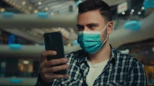 病気の男性ユーザー不健康な男は 医療マスク顔マスクマスク呼吸器隔離規則のショッピングセンターに座っている ビジネスマンは 携帯電話のブラウジングウェブ上でオンライン時計のビデオコンテンツをチャットWi Fi接続を使用 — ストック動画
