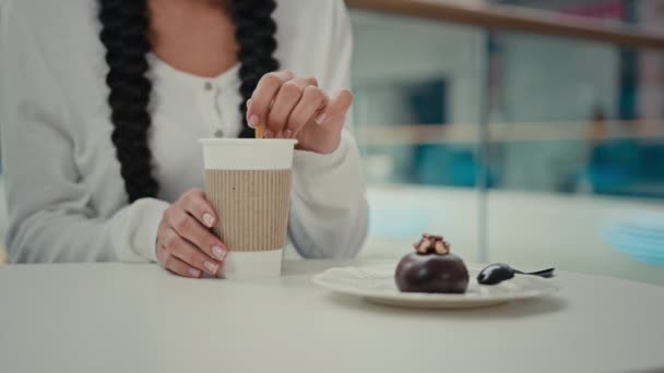 ブルネットの若い女性の顧客学生はカフェテーブルカフェテリアレストランでコーヒーとチョコレートデザートを購入甘いケーキは使い捨てカップカフェインホットアロマ飲料で砂糖カプチーノラテドリンクを攪拌 — ストック動画