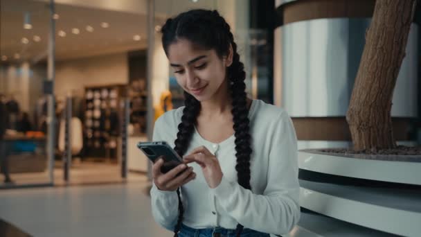 中東の女の子のビジネス女性アラビアの民族の女性の買い物客は インターネットストアでショッピングモールの購入に座ってオンラインでチャット携帯電話のガジェットを使用して良いニュースのテキストメッセージを読む — ストック動画