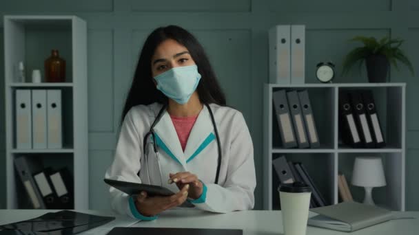网上摄像头咨询年轻外科医生阿拉伯女医生戴面具说话视频呼叫无线帮助在医院使用医疗数字应用程序在平板电脑在线教学中的应用 — 图库视频影像
