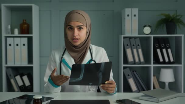 网上摄像医生年轻的放射学家妇女在Hijab网上咨询病人通过计算机视频会议应用程序显示磁共振伦琴相机使用电信技术进行虚拟医疗检查 — 图库视频影像