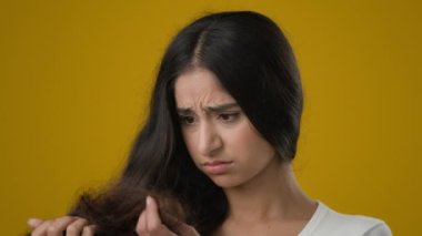 Depresyondaki Hintli etnik kadın bayan esmer kadın saç stiline bakıyor. Hasarlı saç dökülmesi, saç dökülmesi, alopesya hormon sorunları ya da vitamin eksikliği konusunda endişeli.