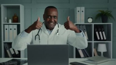 Duygusal açıdan mutlu erkek doktor, beyaz önlüklü, dişçi, pratisyen, Afrikalı kardiyolog, sağlık sigortası aşısı yapılmasını öneriyor.