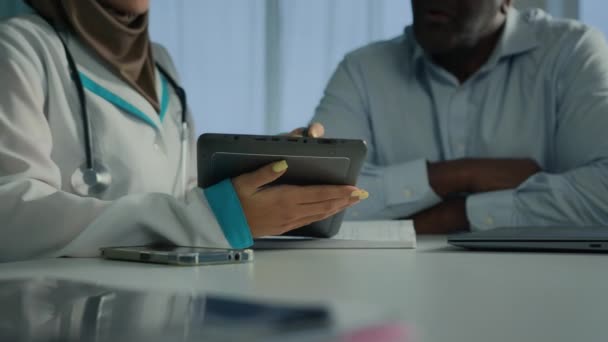ヒジャーブ州の若い医師女性医療従事者看護師は アフリカの高齢者へのWeb画面上の健康テスト結果を示す電子デジタルタブレットを使用して専門家の勧告を聞く治療を議論 — ストック動画