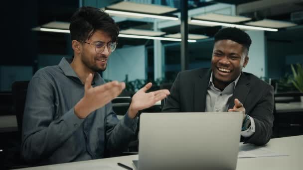 男性アフリカ系インド人同僚労働者男性幸せなビジネスの人々ビジネスマンはコンピュータ画面を見て笑って楽しいユーモアを話して笑いを見て面白いビデオでオフィス企業のパートナーシップ — ストック動画