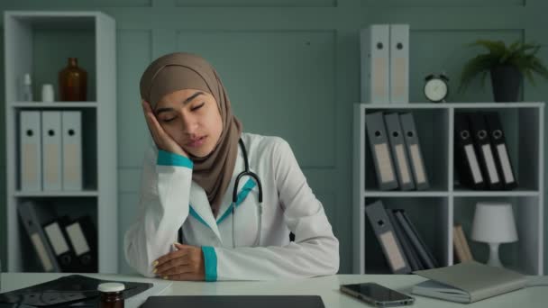 闷闷不乐 心事重重的女穆斯林医生实习生坐在办公室诊所感到悲伤 精神障碍 忧郁症 认为抑郁症思想懒惰 缺乏动力的医生在大脑皮层病毒大流行后疲倦了 — 图库视频影像