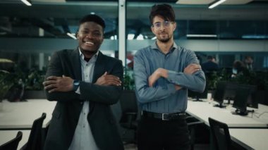 Çok ırklı iş arkadaşları, Arap ve Afrikalı iş adamlarına gülümsüyor. İş arkadaşları, kollarını kavuşturup, başarılı erkek takım çalışmalarına poz veriyorlar.