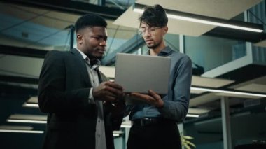 İş ortakları erkek işadamları ofiste duruyor Afrikalı bankacı ajan dizüstü bilgisayarla Arap müşteriye danışarak banka kredisi yardımlarını tartışıyor online web sitesi geliştiriyor iki etnik adam müzakere ediyor