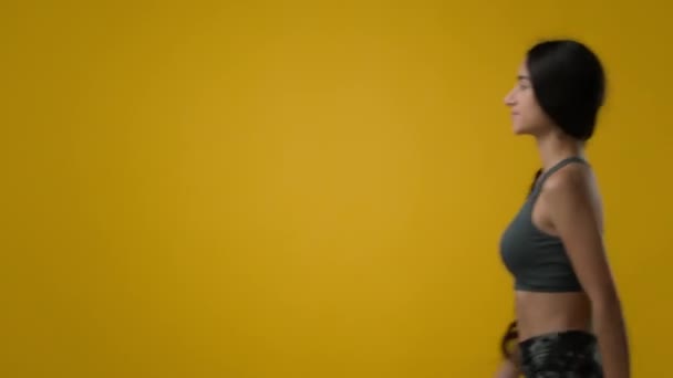 空余的复制空间在黄色的背景下苗条身材瘦弱瘦弱的印度女运动员女体育运动女模特儿在演播室里走着走着走着走着走着一边看着走着适合的女士去锻炼着赶着去体育馆 — 图库视频影像